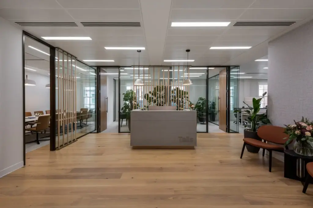 Talis Capital reception with a concrete-clad desk engraved with the Talis logo, in front of timber veneer slat screens
