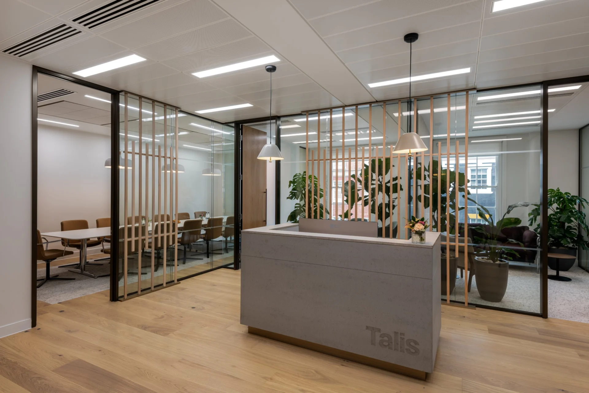 Concrete-finish reception desk with routed Talis lettering and a recessed bronze-effect plinth at Talis Capital